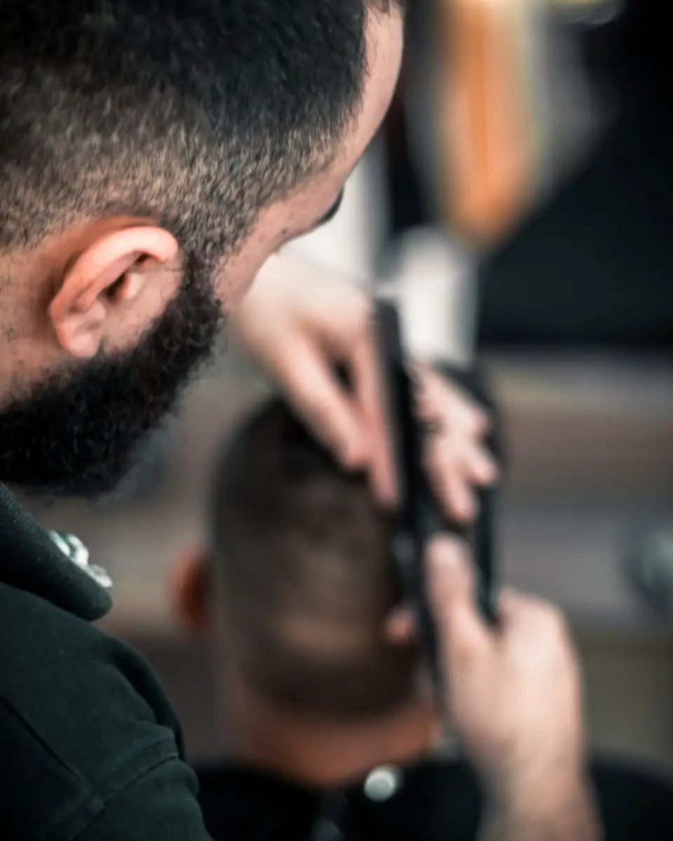 Barber using clippers on the side of a customer’s head