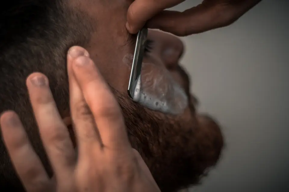 Close-up of a straight razor shaping a beard line