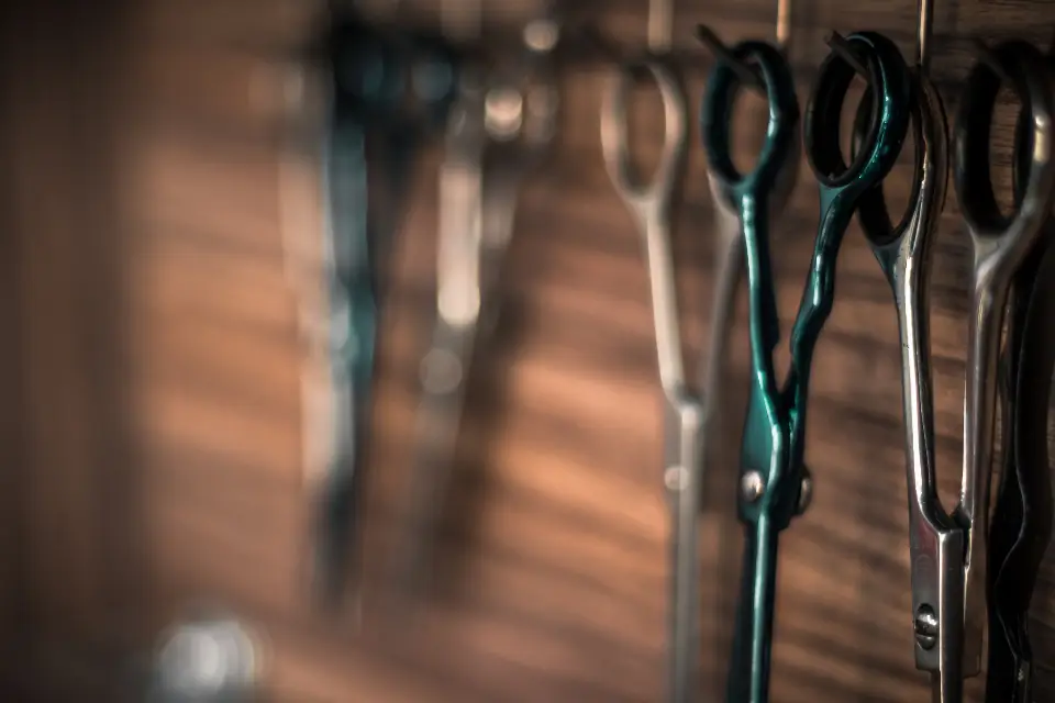 Barber scissors hanging on a wooden wall rack