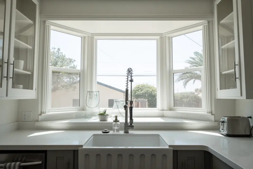 Bright farmhouse kitchen with a white sink and chrome faucet under a window